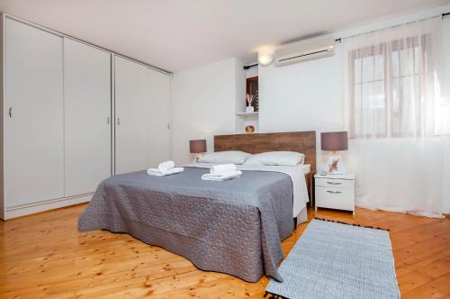 a white bedroom with a bed and a blue rug at Apartment Marconi in Rovinj