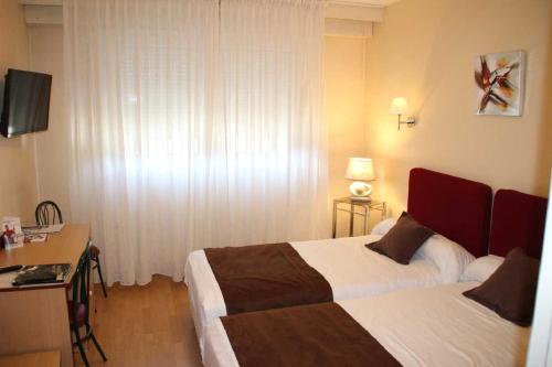 a hotel room with two beds and a desk at Hôtel Saint-Hubert in Saint-Claude