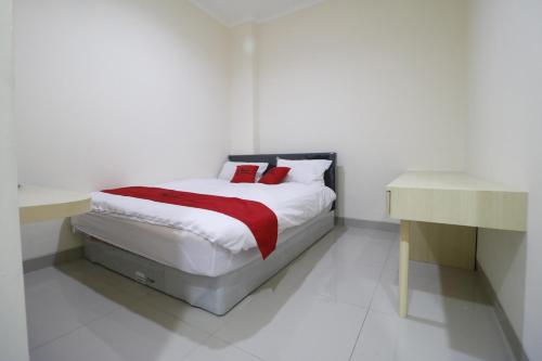 um quarto branco com uma cama e uma secretária em RedDoorz Plus near Mall Ciputra Jakarta em Jakarta