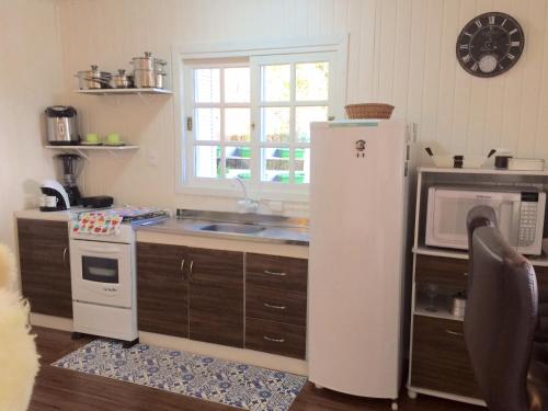 a kitchen with a refrigerator and a microwave at Chalé Vale do Floresta in Gramado