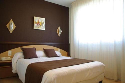a bedroom with a large bed and a window at Hôtel Saint-Hubert in Saint-Claude