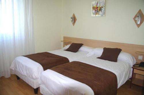 two beds sitting next to each other in a hotel room at Hôtel Saint-Hubert in Saint-Claude