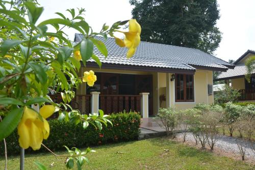 a small house with yellow flowers in front of it at Apple Bungalows in Bang Saphan