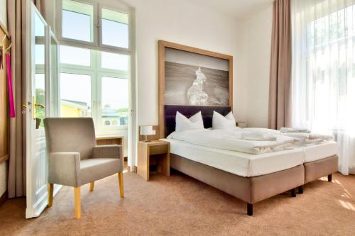 a bedroom with a large bed and a chair at Villa Auszeit Hotel Garni in Bansin