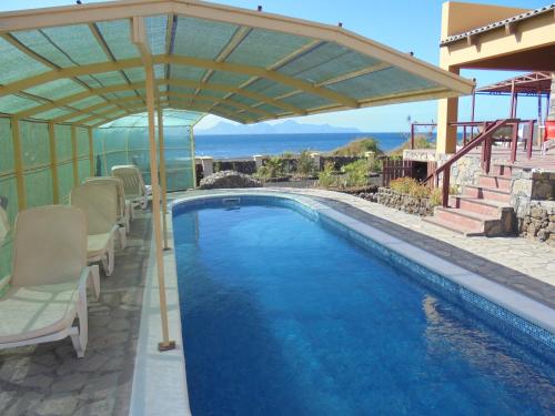 a swimming pool with a pergola on a house at Coin de Paradis,Pavillon Doucimar in Porto Novo