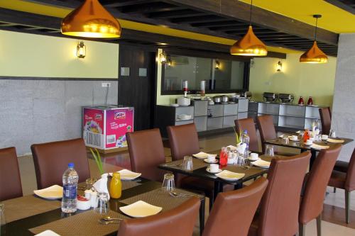 a restaurant with tables and chairs and a kitchen at Vinayaga by Poppys ,Kumbakonam in Kumbakonam