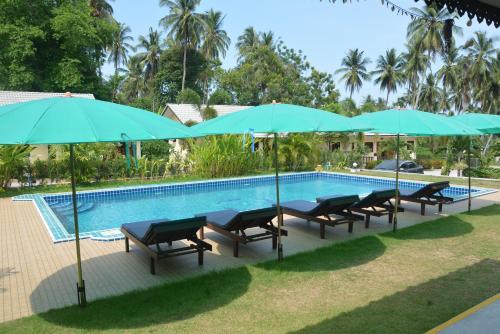 a pool with chairs and umbrellas next to it at Apple Bungalows in Bang Saphan