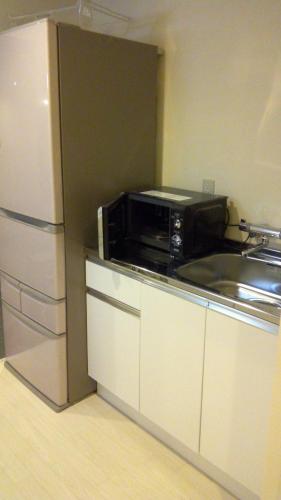 a kitchen with a microwave and a refrigerator at Base Inn Uguisudani in Tokyo