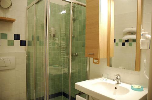 bagno con lavandino e doccia in vetro di Hotel Anapaya a Lignano Sabbiadoro