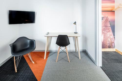 a table with two chairs and a tv on a wall at Norrland YMCA Hostel Umeå in Umeå