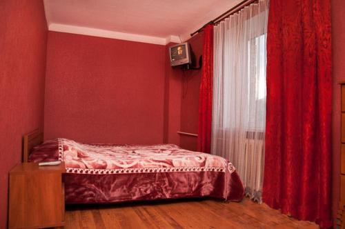 キーウにあるквартираのベッドルーム1室(赤い壁のベッド1台、窓付)