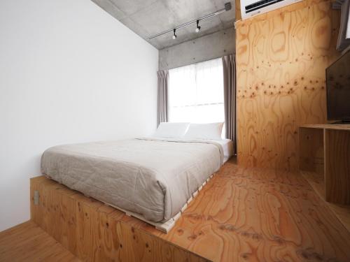 a bedroom with a large bed and a window at Smi:re Stay Oshiage in Tokyo