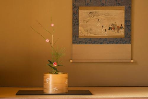 a plant in a pot on a table with a painting at Arima Onsen Takayamaso Hanano in Kobe