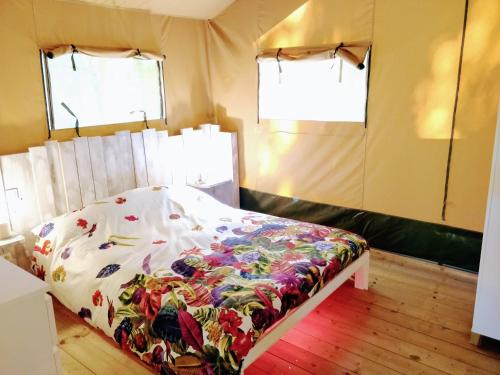 a bedroom with a bed in a room with two windows at La Fortinerie Glamping Safari Tent with Hot Tub in Mouliherne