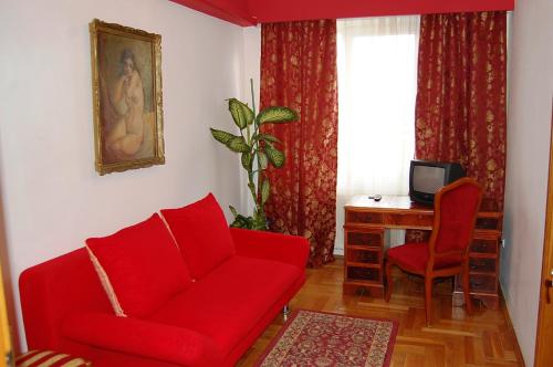 a living room with a red couch and a desk at Pensiunea Sydney in Timişoara