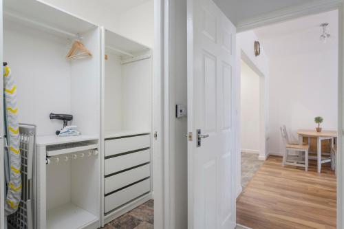 a room with a closet with white cabinets and a table at 1 Bed Apt Sleeps 4 in Luton