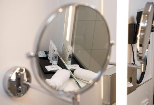 a mirror in a bathroom with towels and a toothbrush at Mercure Hotel Mannheim am Friedensplatz in Mannheim