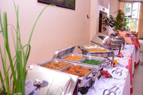 a buffet with several trays of food on a table at Beausejour Hotel in Kigali