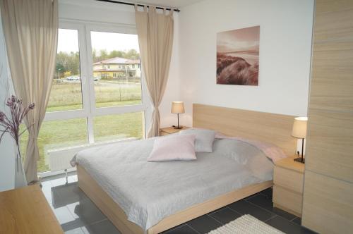 - une chambre avec un lit et une grande fenêtre dans l'établissement Apartments zum Strand, à Wendisch Rietz