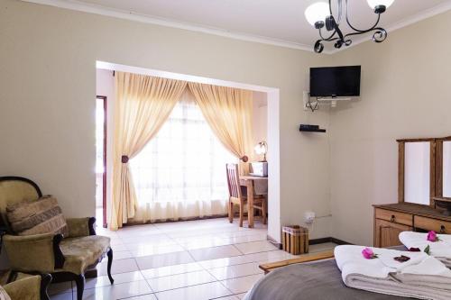 a bedroom with a bed and a living room with a window at Holme Lea Manor in Piet Retief