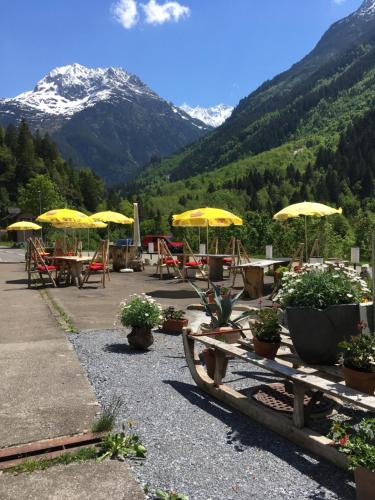 a group of tables and chairs with yellow umbrellas at "Terrasse" Nessental in Gadmen