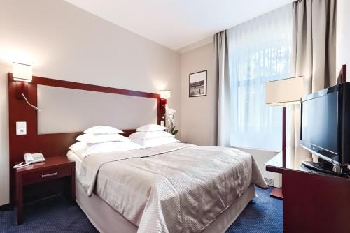 a hotel room with a bed and a flat screen tv at Hotel Atrium in Szczecin