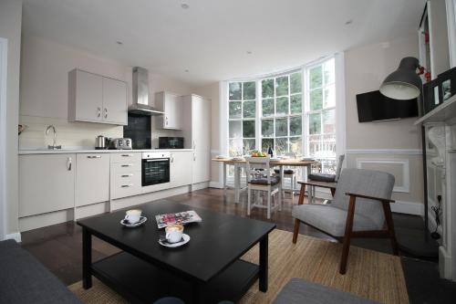 a living room with a table and a kitchen at Number 18 Apartments in Exeter