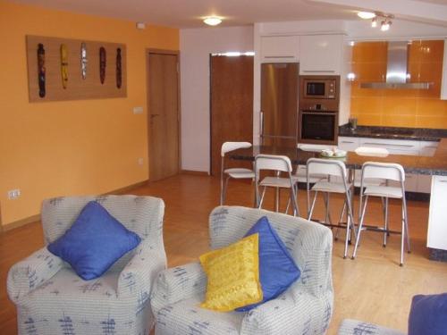 sala de estar con 2 sillas y cocina en Ático nuevo en playa de Laxe, en Laxe