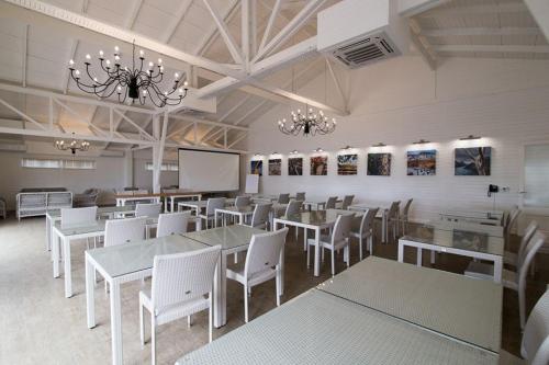 a dining room with white tables and white chairs at Tete Ferry Sun in Vila-de-Santiago-Maior