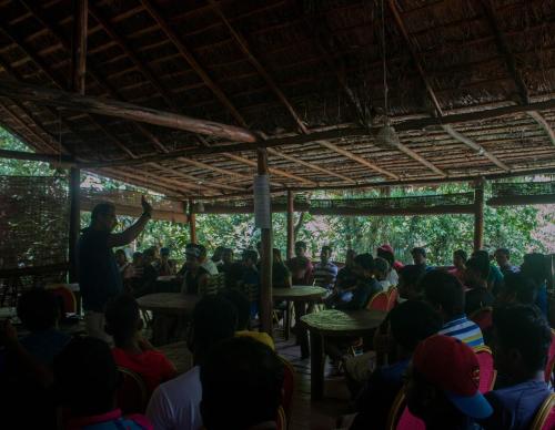 a man giving a presentation to a crowd of people at Jungle River in Ginigathena