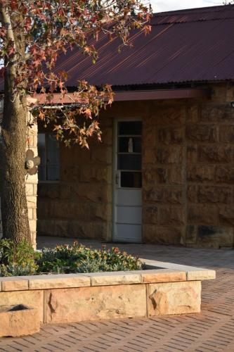 a building with a tree in front of it at Makoadi Farms Guesthouse in Clocolan