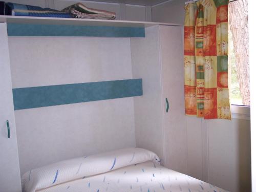 a room with a bed and a shelf and a window at Camping Cobijo in Vinuesa