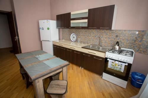 a kitchen with a stove and a sink and a table at Guesthouse Hillside in Tbilisi City