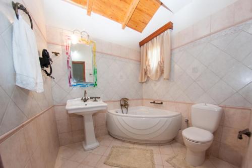 uma casa de banho com um lavatório, um WC e uma banheira em SunRise Vila em Lixúri