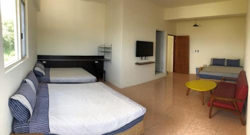 a bedroom with two beds and a table and a television at Fire Island Guest House in Green Island