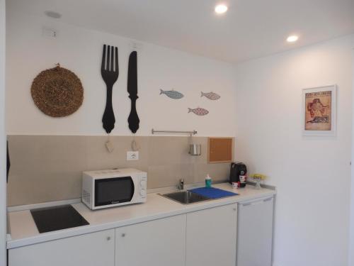 cocina con fregadero, microondas y utensilios de cocina en Maiolica guest house,a delicious studio, en Siracusa