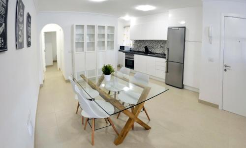 a white kitchen with a glass table and white chairs at Iriarte Serenity with FREE PARKING in Puerto de la Cruz