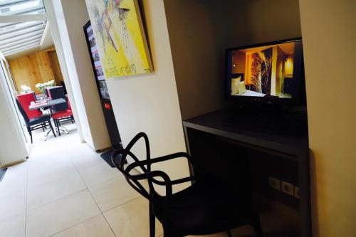 a living room with a chair and a television at Hôtel Brésil Opéra SPA in Paris