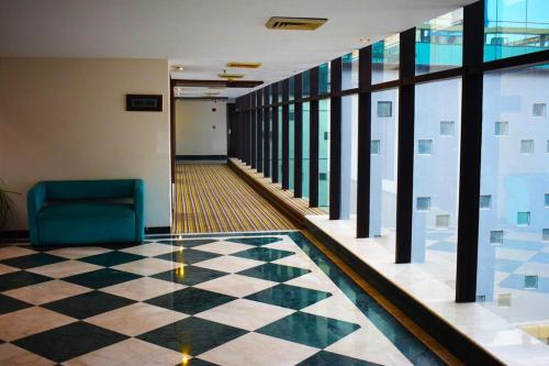 a lobby with a checkered floor and a blue chair at Hotel Sewa Grand Faridabad in Faridabad