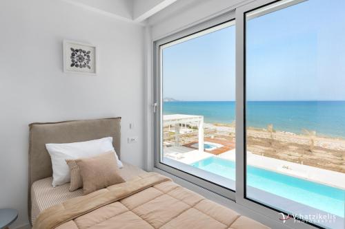 a bedroom with a bed and a view of the ocean at Maria & Nada Beachfront Villas in Kolimbia