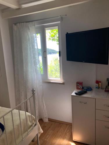 a bedroom with a bed and a window and a television at Guest Accommodation Sveti Jakov in Dubrovnik