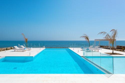 a swimming pool with the ocean in the background at Maria & Nada Beachfront Villas in Kolymbia