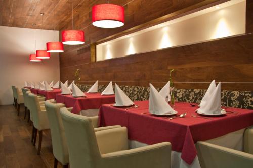 a row of tables in a restaurant with red table cloths at Casa Inn Premium Hotel Queretaro in Querétaro