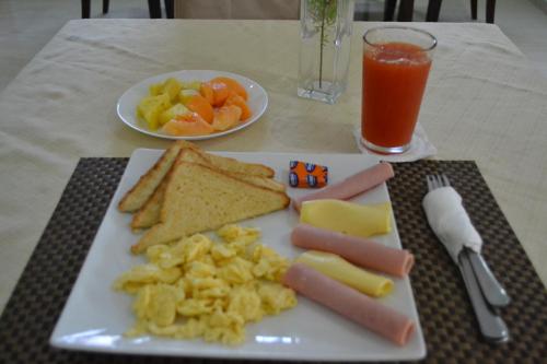 a plate of food with sausage cheese crackers and a drink at Hotel Renacer in Santo Domingo