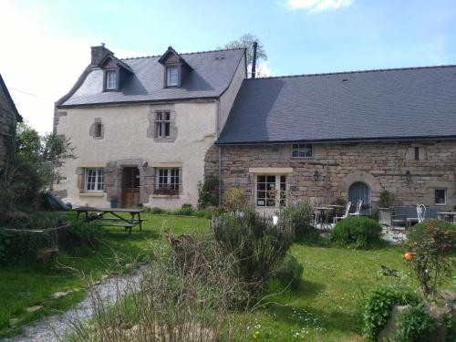 an old stone house with a picnic table in the yard at Frairie Du Divit in Pontivy