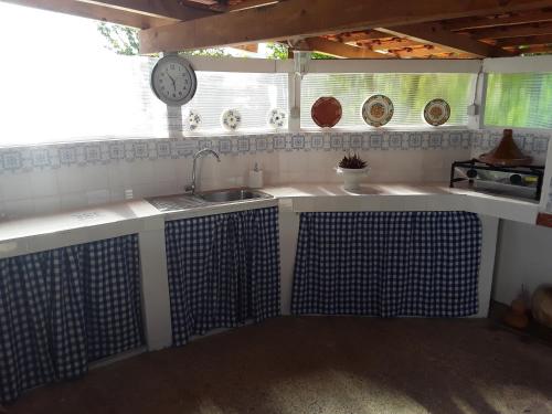een keuken met een wastafel en een klok aan de muur bij Quinta Camargue in Cela Velha