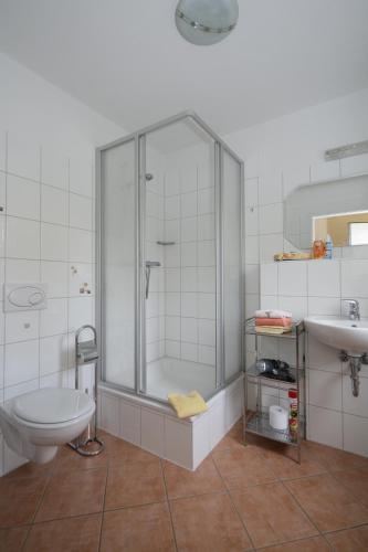 a bathroom with a shower and a toilet and a sink at Haus Freyja Ferienwohnungen in Graal-Müritz