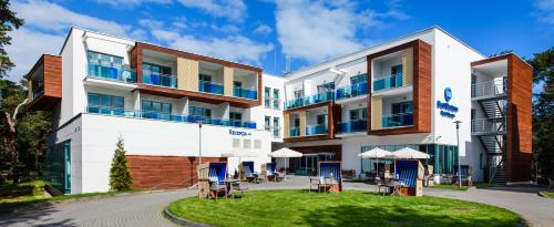 an exterior view of a hotel with tables and umbrellas at Best Western Hotel Jurata in Jurata