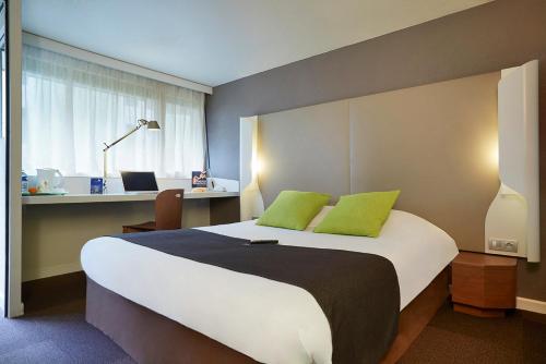 um quarto com uma cama grande e almofadas verdes em Kyriad SEDAN em Sedan