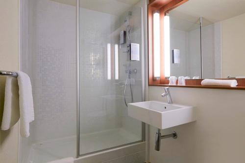 La salle de bains est pourvue d'une douche en verre et d'un lavabo. dans l'établissement Kyriad SEDAN, à Sedan